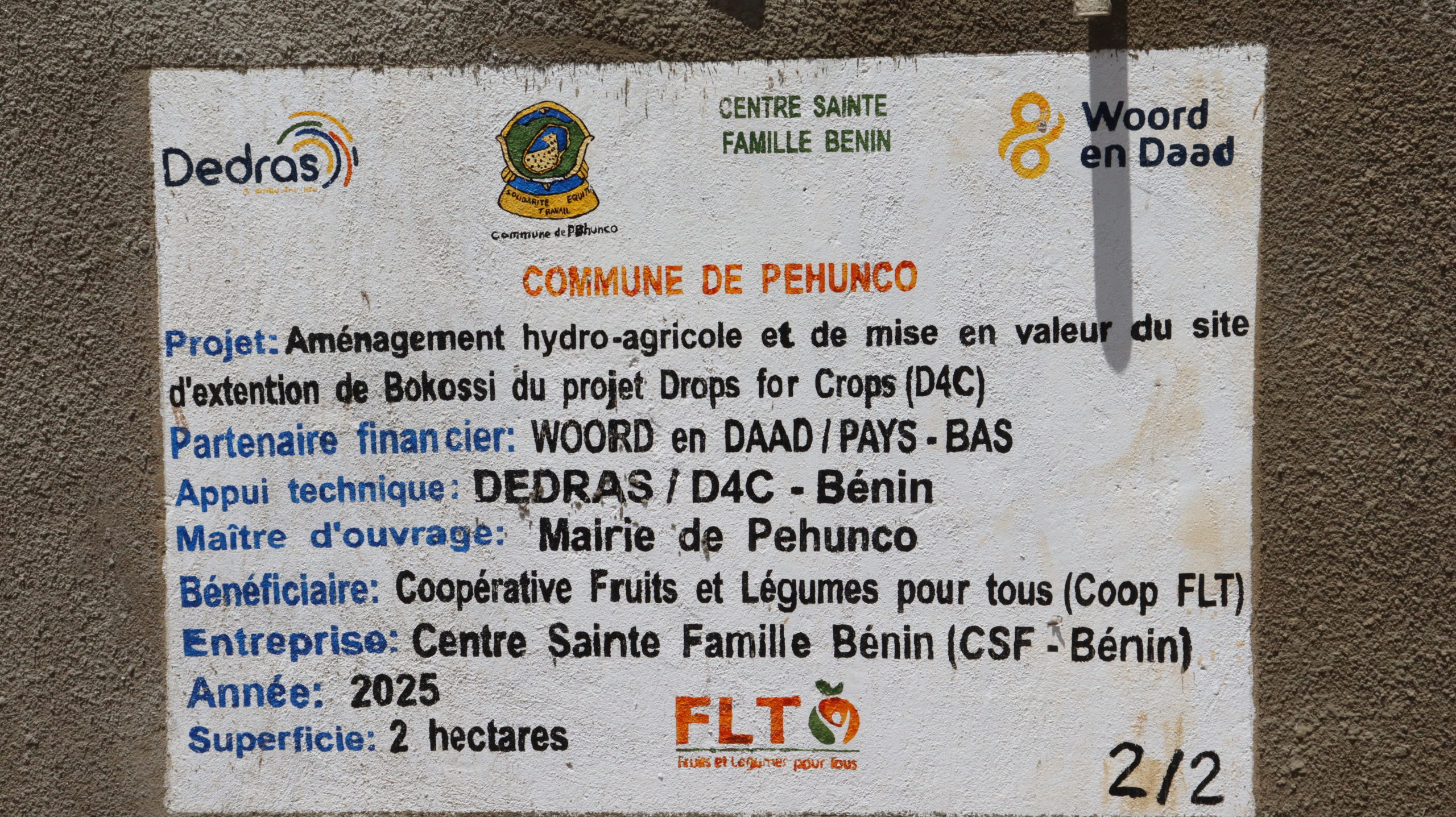 Panneau de chantier portant les noms de la commune, de DEDRAS et de Woord en Daad sur le site aménagé de Bokossi